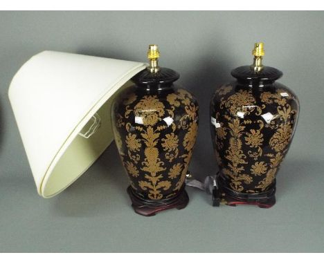 A large pair of ceramic table lamps with stylised floral decoration against a black ground, approximately 49 cm (h) to top of