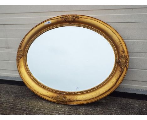 An oval framed, bevel edge wall mirror, approximately 88 cm x 67 cm.