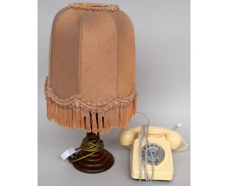 A cream rotary dial phone, together with a table lamp with fringed shade, 56cmH