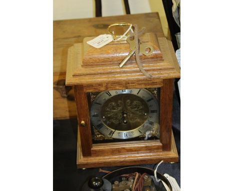 Comitti of London mantel clock, the brass dial with Roman numerals, housed in a wooden case, the face decorated with brass fa