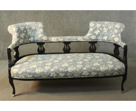 A circa 1900 ebonised sofa, upholstered to the back rail and seat with grey fabric decorated with a white vine design, the ba