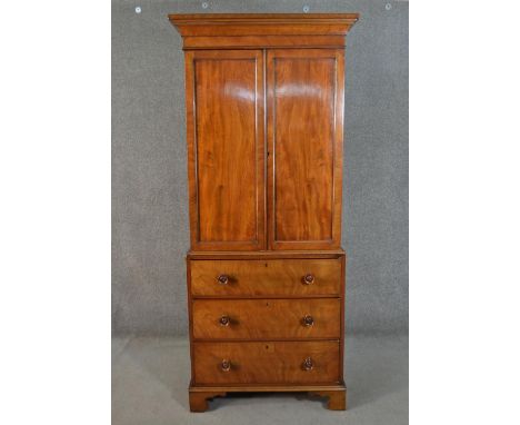 An early 19th century mahogany linen press, of narrow proportions, with two cupboard doors, converted with a brass hanging ra