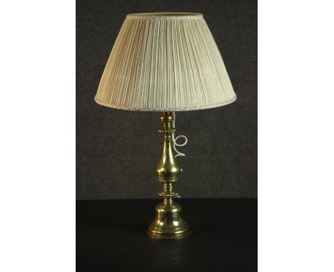 A brass candlestick, converted to a lamp, with a baluster and turned body, and a pleated shade. H.60 Dia.35cm. 