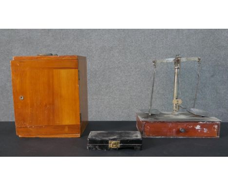 A set of early 20th century weighing scales with a set of brass weights along with a boxed Bausch &amp; Lomb microscope with 