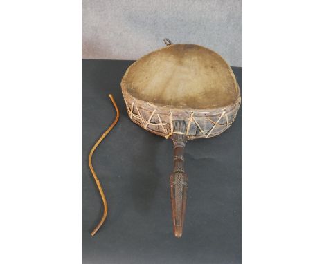 An African hide and gut drum with carved handle and beating stick.  L.67 W.37cm 