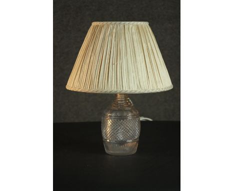 A 19th century cut glass decanter, converted to a table lamp, with a diamond cut body and a pleated shade. H.41 Dia.31cm. 