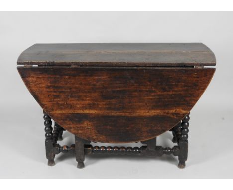 A late 17th/early 18th century oak gate-leg dining table, the oval top on bobbin turned supports united by conforming stretch