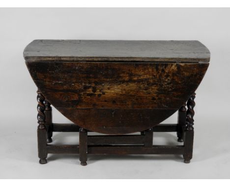 A late 17th century oak gate leg dining table the oval top on barley twist supports united by plain side stretchers raised on