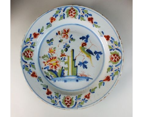 A Lambeth Delftware polychrome dish, mid-18th century, painted with a parrot perched on a branch beside a rock and flowers, f