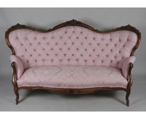 A Victorian button back Louis XV style settee with walnut leaf carved show frame re-covered in a salmon pink damask style mat