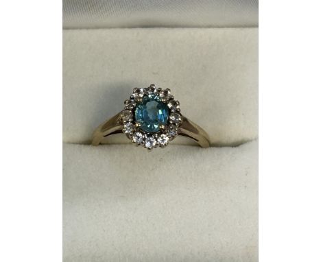 9ct gold dress ring set with central blue stone surrounded by white stones. Size O