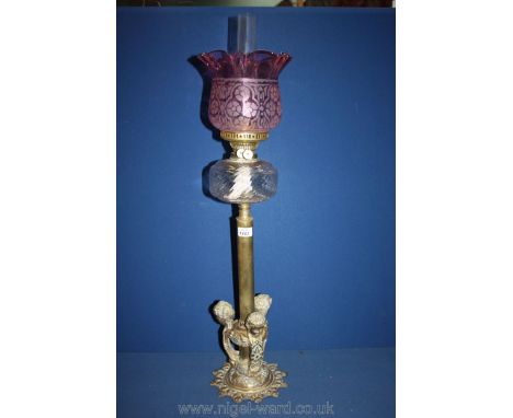 A heavy tall Brass Oil Lamp with spiral reservoir and cranberry style shade, three mounted cherubs to base