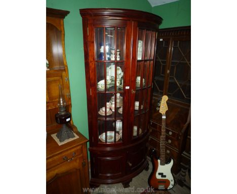 A bow fronted Mahogany corner Vitrine/Display Cabinet having a pair of bevelled glazed doors and raised and fielded panelled 