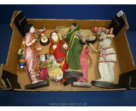 A bone figure of a snake charmer on a wooden plinth with an Indian sculptural figure and Indian vintage dolls.