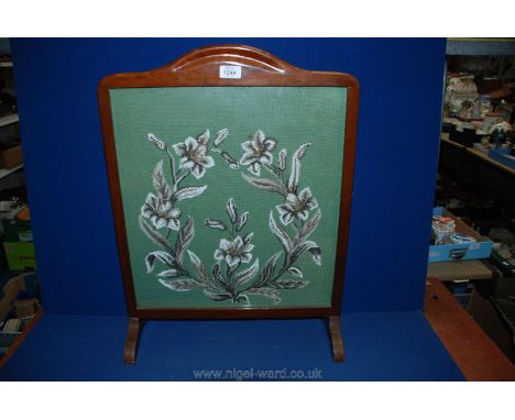 A cross-stitched firescreen.
