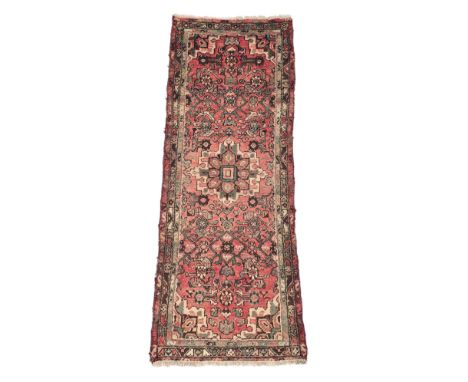 A Persian Hamadan woollen hand knotted runner with central motif, on a red ground, 181 by 65cms.