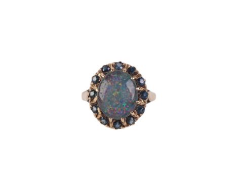 A 9ct gold ring set with a large oval opal doublet surrounded by pale blue stones, approx UK size I, 3.5g.