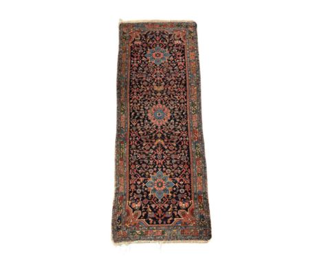 A Persian Hamadan runner with three central medallions, on a pale red ground, 109 by 305cms.