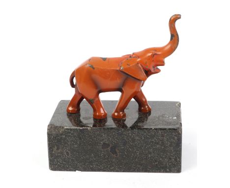 An Art Deco lacquered metal figure of an elephant with an upraised trunk, mounted on a polished granite stand, overall 15cms 