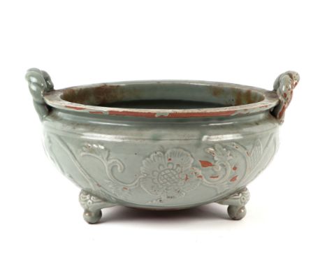 A large Chinese celadon glaze twin-handled tripod censer or planter, decorated with scrolling flowering foliage, 35cms wide.C