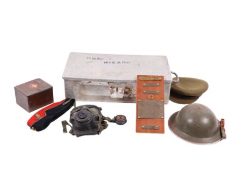 A quantity of military items to include uniform, peaked caps, helmet, gas mask contained in an HMS Wizard aluminium trunk.