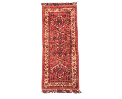 A Persian Turkoman hand knotted runner with repeating guls on a red ground within a multi border, 70 by 156cms.