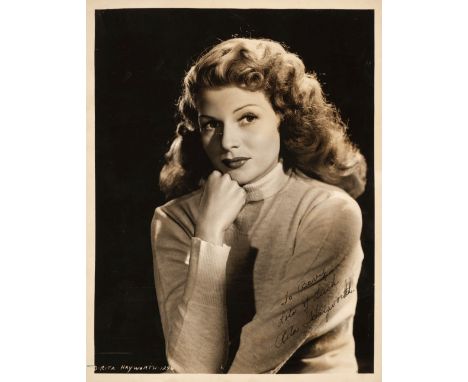 * Hayworth (Rita, 1918-1987). A vintage signed and inscribed glossy photograph, half-length portrait in a turtle-neck sweater
