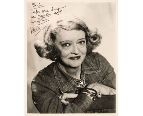 * Davis (Bette, 1908-1989). A signed and inscribed glossy photograph, head and shoulders portrait with arms folded, signed an