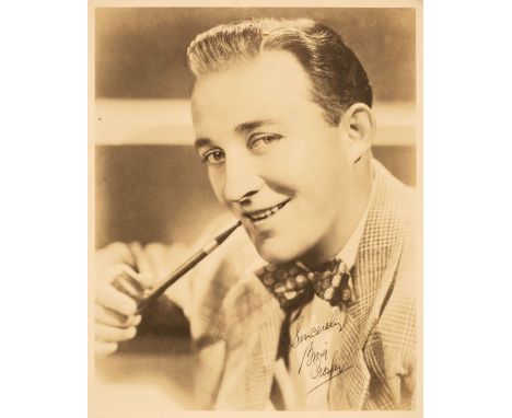 * Crosby (Bing, 1903-1977). A vintage signed photograph, head and shoulders portrait with jacket and bow tie and a held pipe,