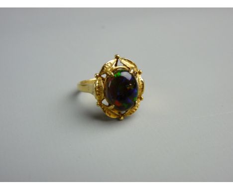 AN EIGHTEEN CARAT GOLD BLACK OPAL DRESS RING having an oval cabochon cut opal in a fancy leaf basket, opal size approximately