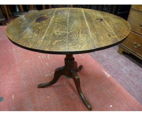 AN ANTIQUE OAK CIRCULAR TOPPED TABLE, the 84 cms diameter top on a turned column tripod base, 69.5 cms high