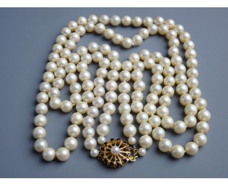 A DOUBLE NECKLACE OF SIMULATED PEARLS with fine garnet and pearl decorated circular nine carat gold clasp, 87 grms gross tota