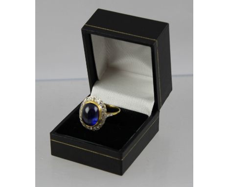 AN OVAL CABOCHON SAPPHIRE AND DIAMOND DRESS RING, the rub over central stone bordered by twenty-one 8/8 cuts, in white and ye