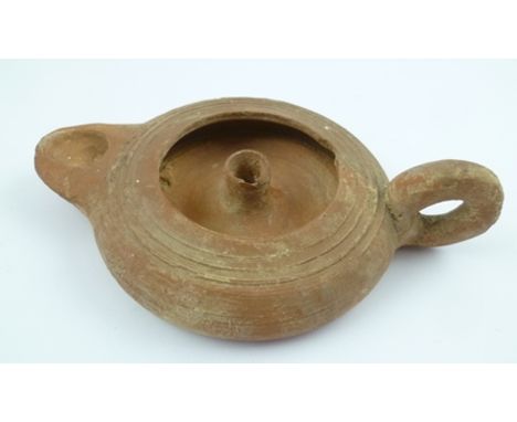 A ROMAN TERRACOTTA OIL LAMP with ring handle, possibly 1st century AD, 15cm high 