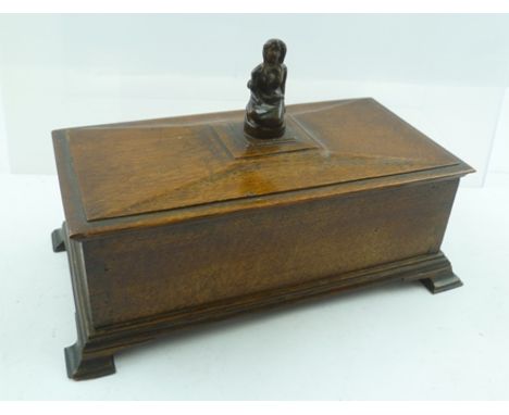 AN EARLY 20TH CENTURY OAK TABLE CASKET, the hinged cover with carved kneeling woman figurative knop, raised on ogee bracket f