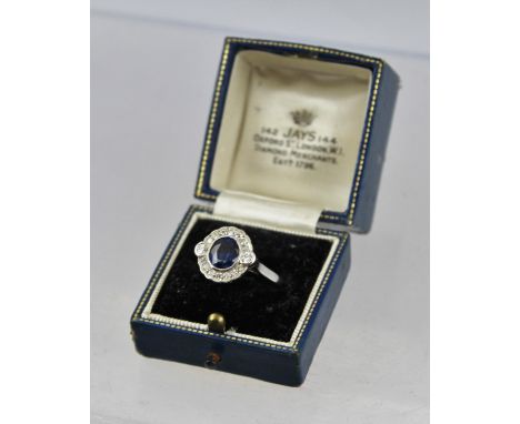 A DIAMOND AND SAPPHIRE CLUSTER RING, having central oval sapphire bordered by sixteen brilliants in rhodium finished white go