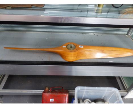 A SMALL WOODEN LAMINATE PROPELLER CENTERED WITH A BAROMETER. 