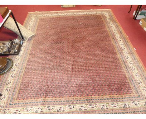 A Persian woollen red ground rug, with repeating central ground, within trailing tramline borders, 320 x 265cmColours are goo