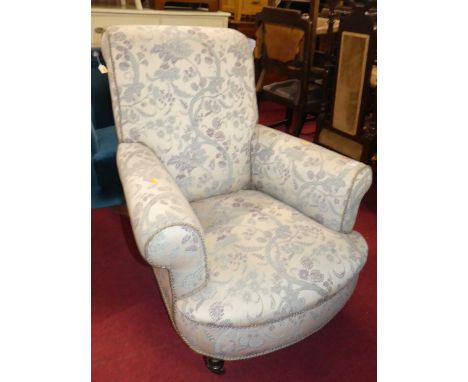 A Victorian mahogany framed and later floral fabric upholstered scroll armchair, raised on squat turned forelegs to castors, 