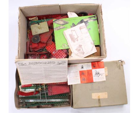 A box containing a collection of vintage Meccano including various flat plates, gear wheels, and other components