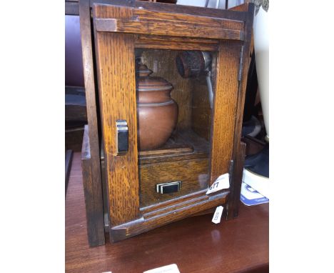 A small Art Deco oak smokers cabinet with tobacco lidded pot and one pipe 