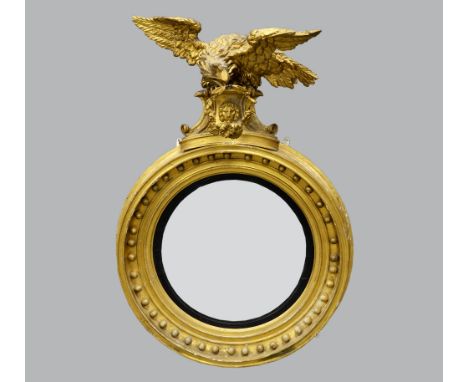 Early 19th century gilt wood and gesso convex wall mirror with eagle finial,  diameter 79cm .    