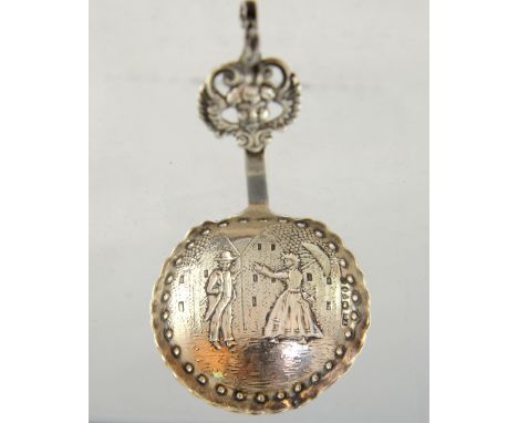 Continental silver caddy spoon, with street scene and two figures decorating the bowl and a lion finial, 11 cm long, 21 g. . 