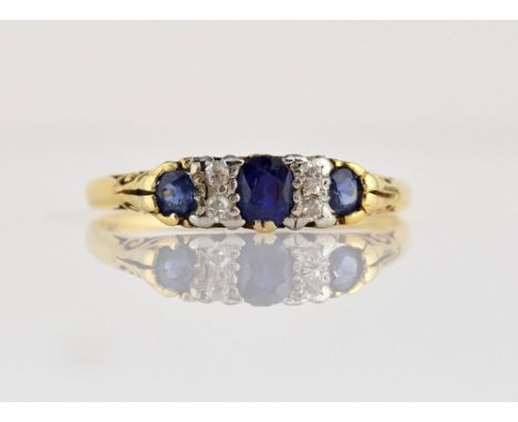 Sapphire and diamond ring, three oval cut blue sapphires set with four Swiss cut diamonds, with decorated scrolled under gall