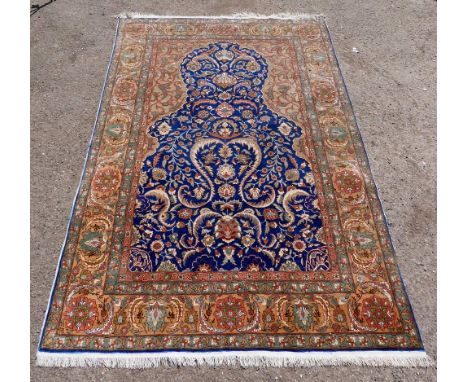 Persian red ground silk rug, with brown border, the centre  with a shaped blue medallion  decorated with floral motifs , 203c