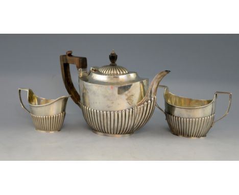 George V silver matched three piece tea service, comprising tea pot, cream jug and sugar bowl, with half-gadrooned bodies, by