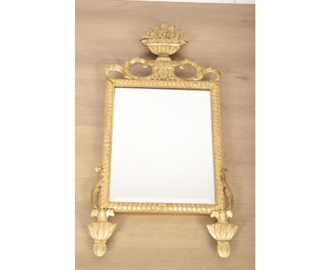 A GEORGE III STYLE CARVED GILTWOOD MIRROR the bevelled rectangular plate within a moulded surround and mounted with an urn cr