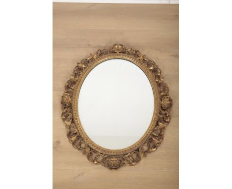 A CARVED GILTWOOD MIRROR the oval plate within an acanthus leaf and shell moulded surround, 66cm high x 55cm wide
