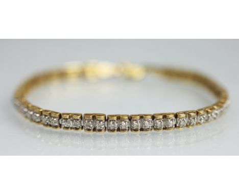 A diamond set tennis style bracelet, set with a central row of diamonds within white metal settings and yellow metal surround