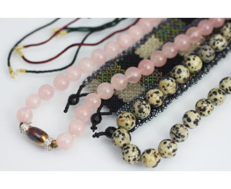 A rose quartz bead necklace and a snowflake obsidian bead necklace, along with a jade coloured bangle, a carved jade entwined